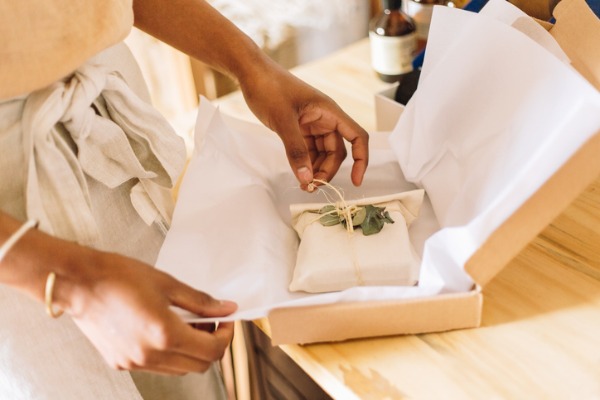 woman packaging goods into foam-lined box for shipping