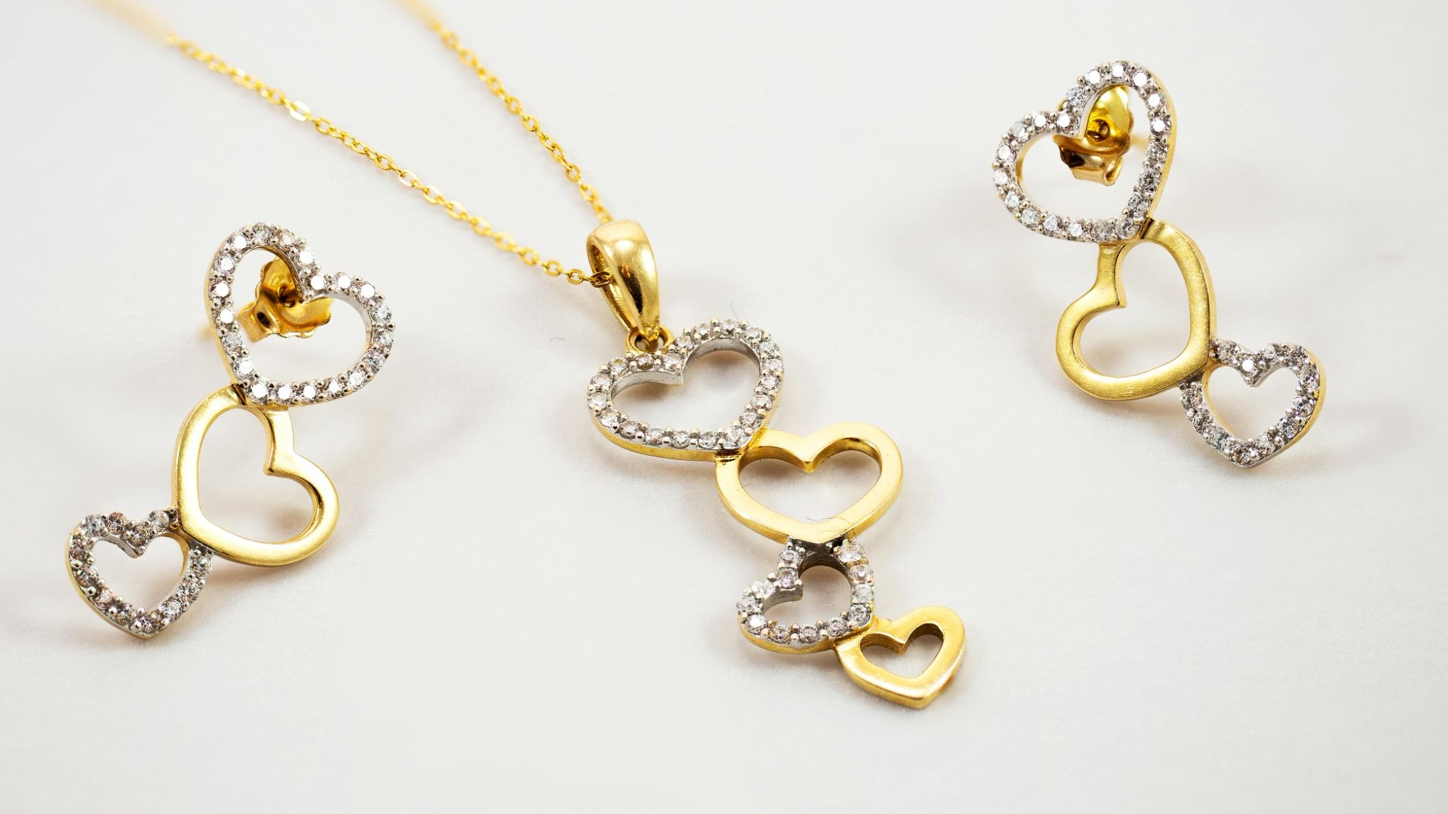 A heart-themed, gold jewellery set consisting of a pair of earrings and a necklace