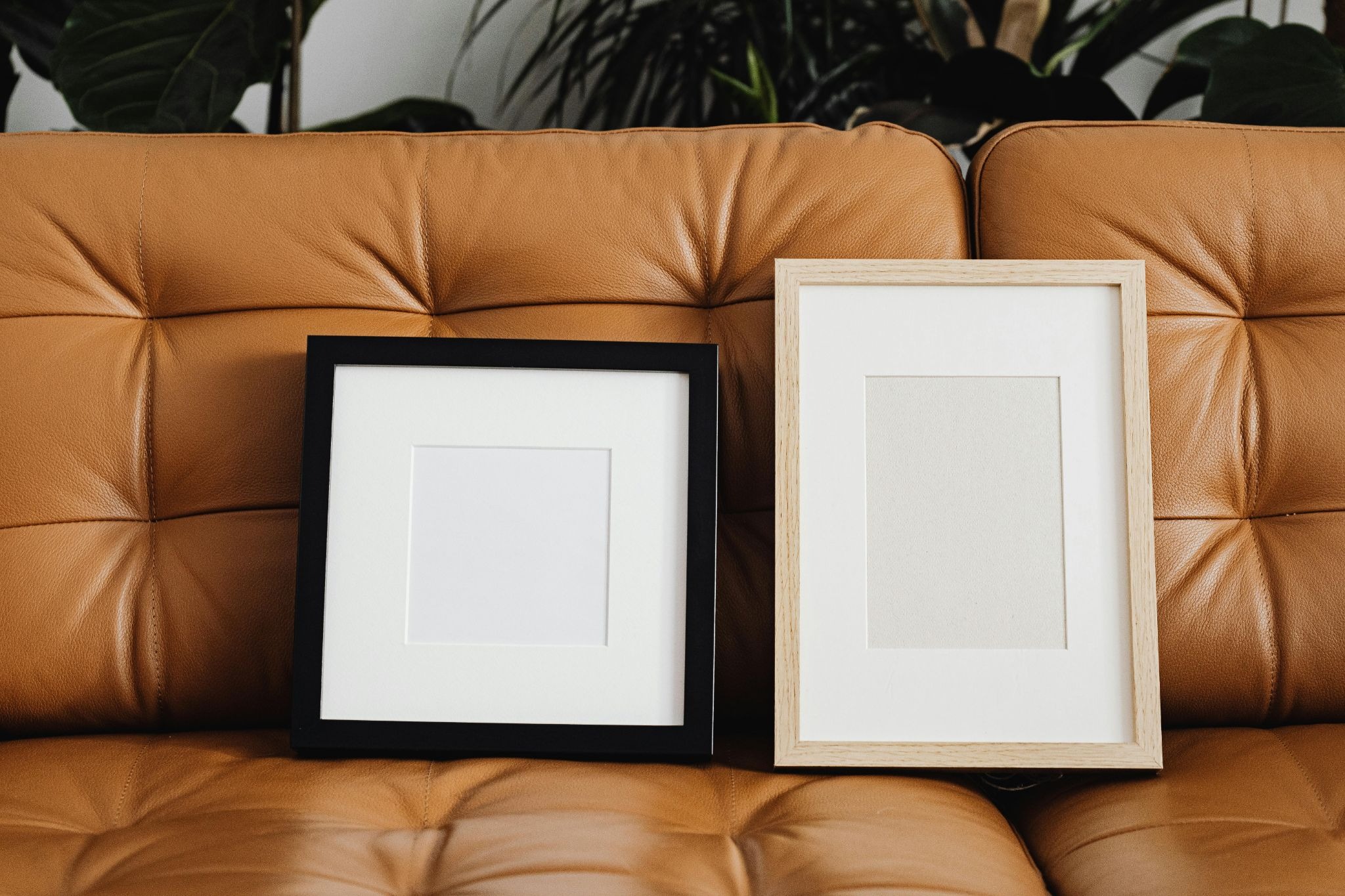 Two empty picture frames placed on top of a brown sofa 