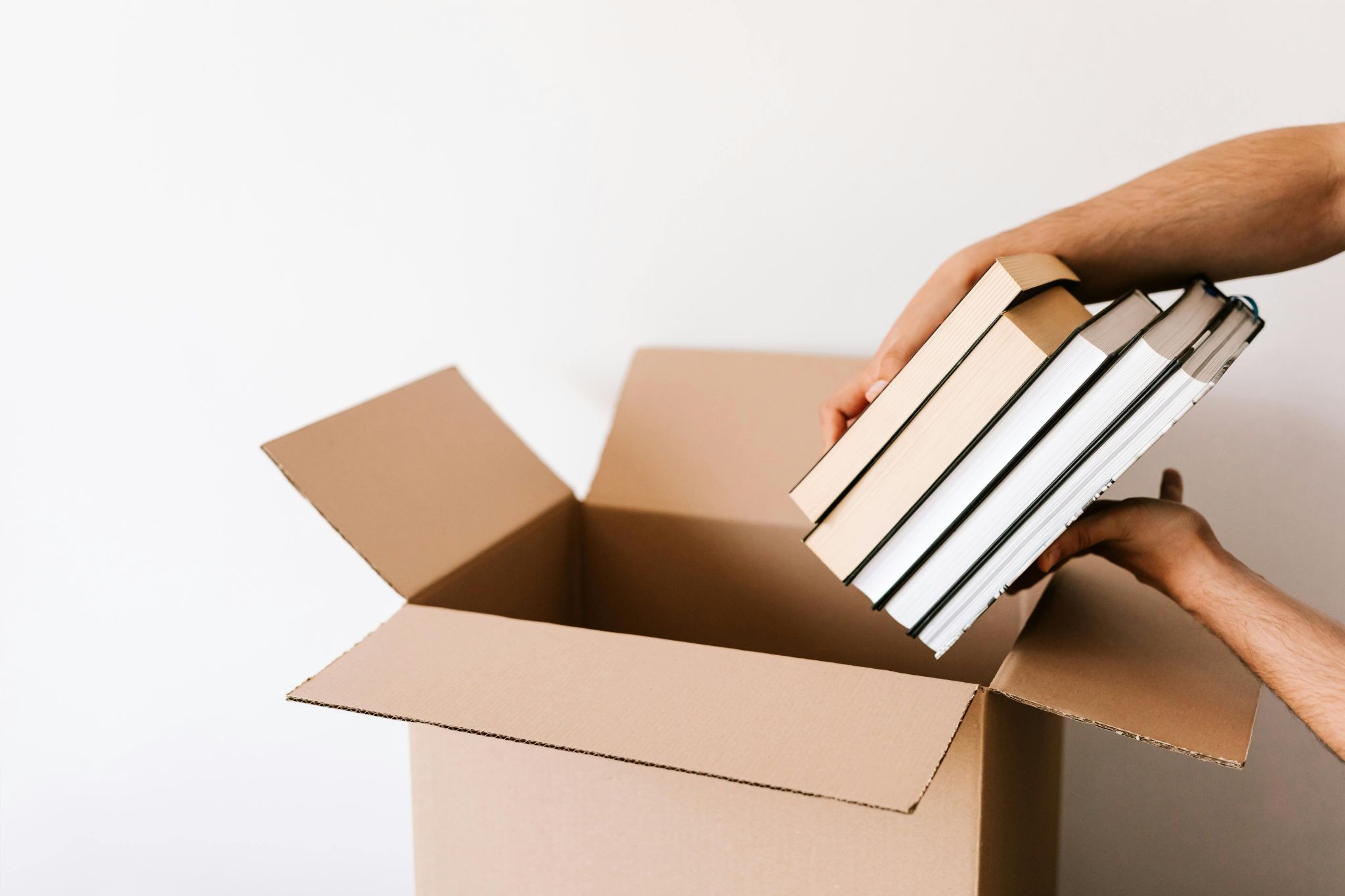 Person packing books inside a box