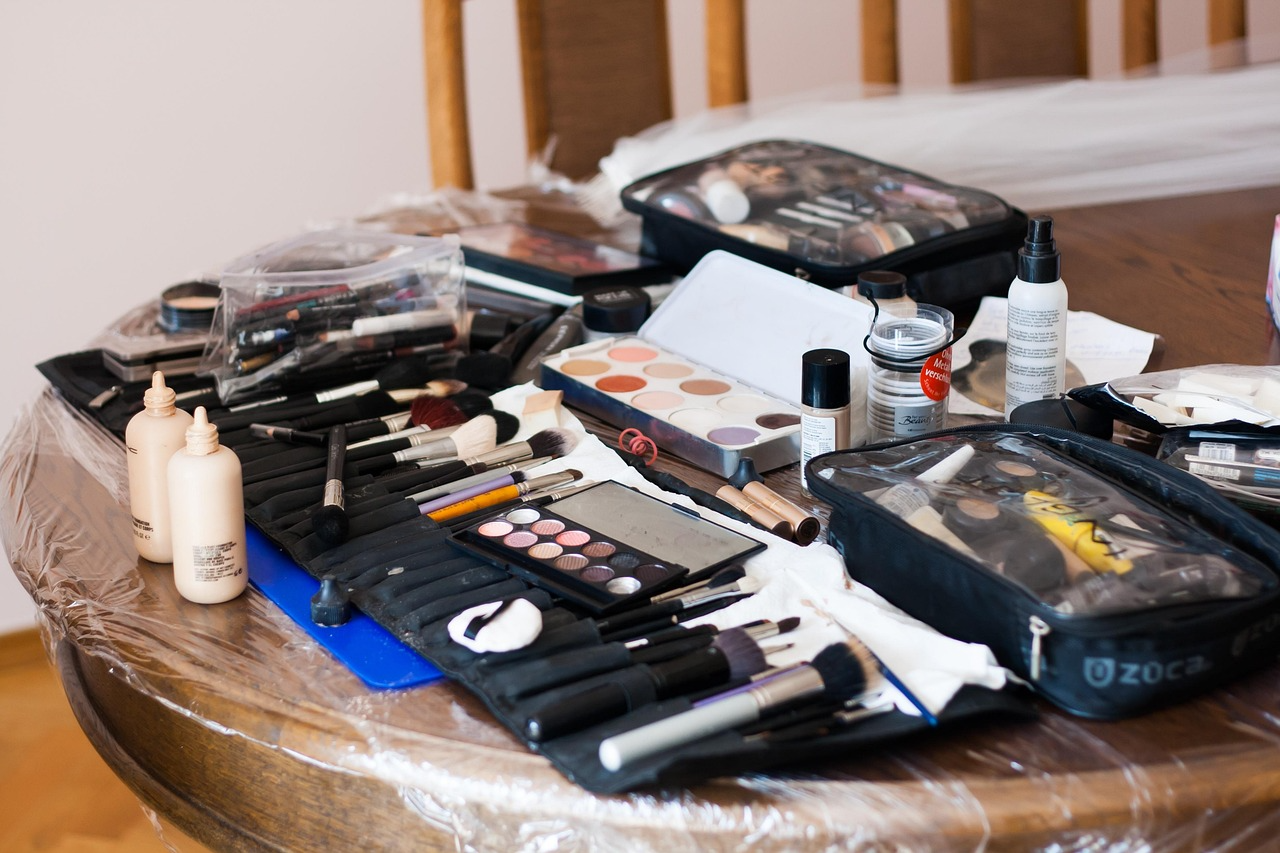 A brown table filled with cosmetic products, including brushes, primers, powders, and concealers.