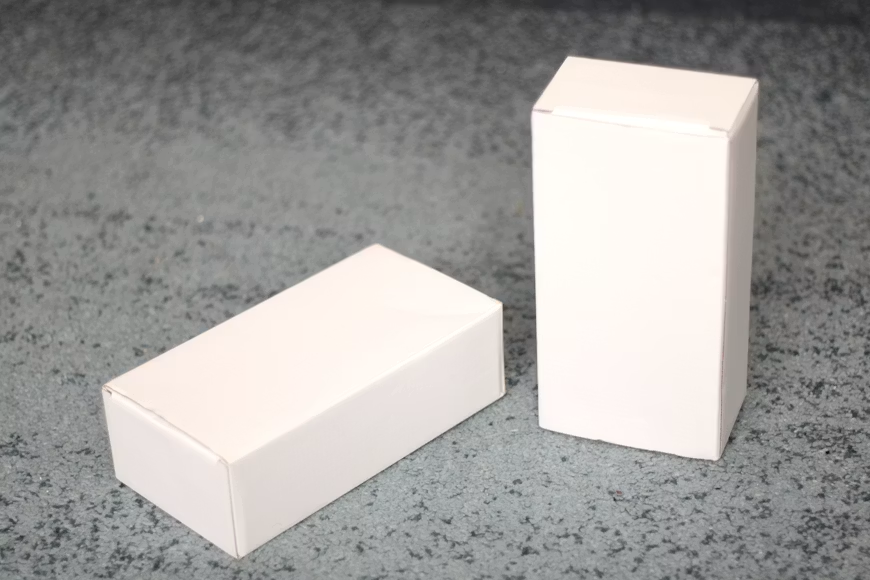 Two white foam lined cardboard boxes on a marble floor.