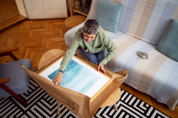 A framed painting arriving safely at home after shipping, with the recipient unboxing it from its packaging.