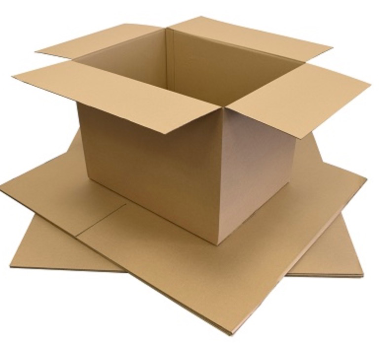 Assembled large brown cardboard box sitting on a stack of flat-packed cartons.