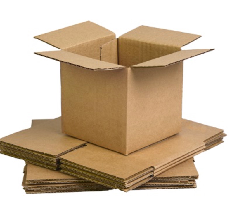Assembled small brown cardboard box sitting on top of a stack of flat-packed boxes.