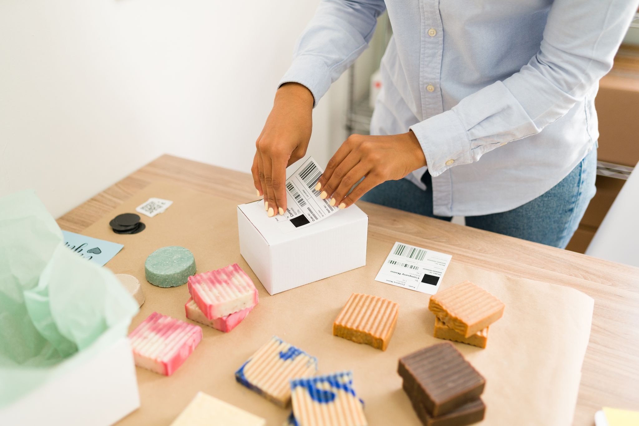 Person applying a printed shipping label to a small white postal box.