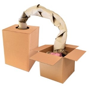 Kraft void fill paper arcing from a dispenser box into an open cardboard box containing a wrapped item.
