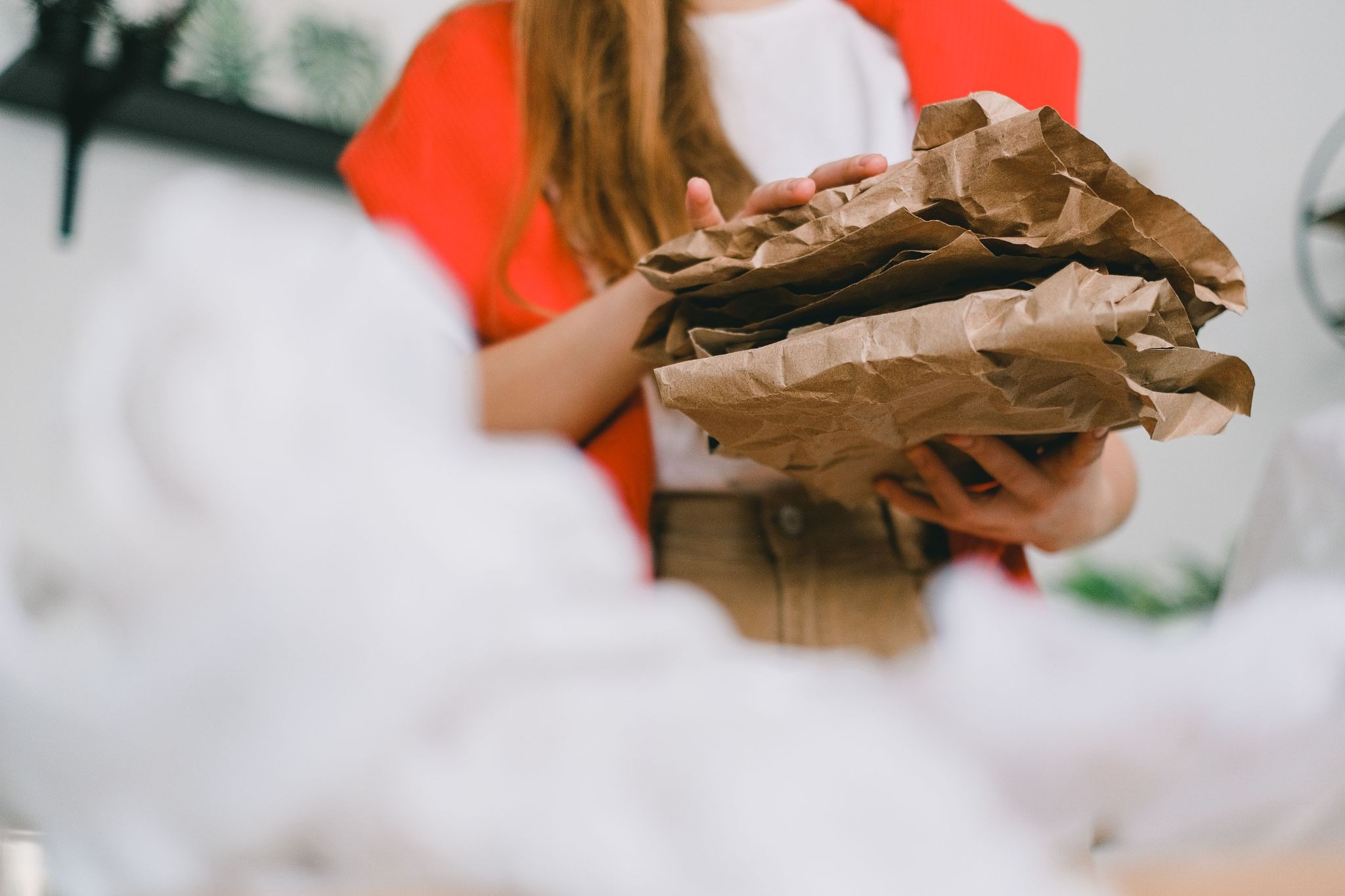 Worker holding crumpled brown paper for protective product packaging.