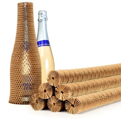 Honeycomb paper bottle sleeves stacked beside a sleeved and an unwrapped bottle, showing a plastic-free way to protect glass in transit.
