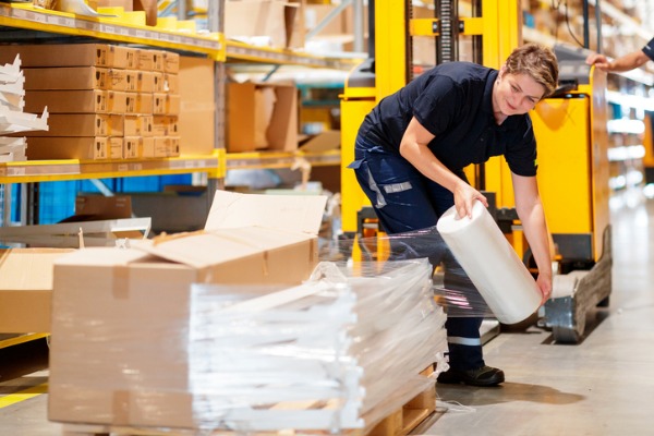 woman in warehouse wrapping pallete for shipment